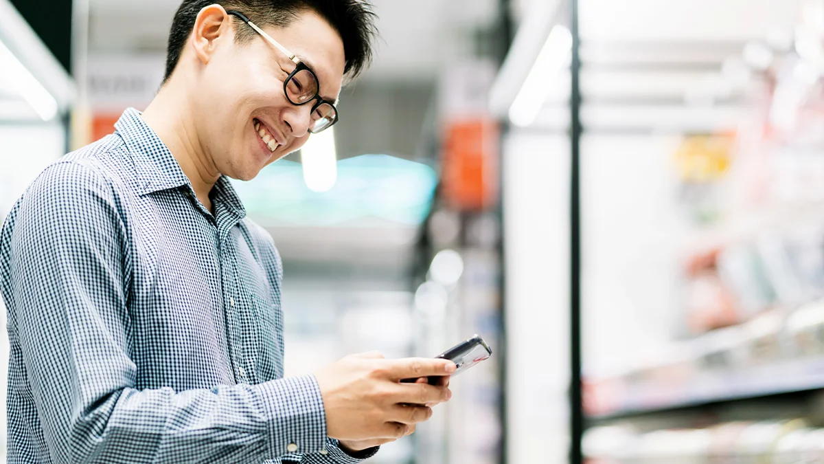 Man smiling and looking at phone in store